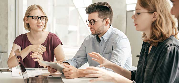 three people discussing work at a round table