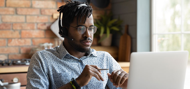 A man studies with headphones and his laptop