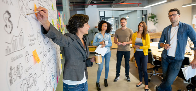 A woman explains information on a white board to her staff