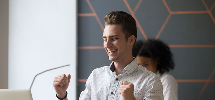 A man is happy about information he sees on his laptop 