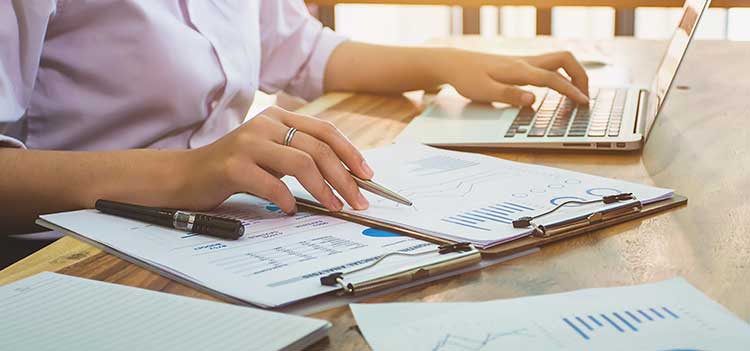 closeup of person's hands taking notes and calculating data