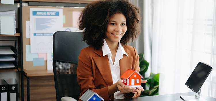 woman insurance agent holds model house in hands
