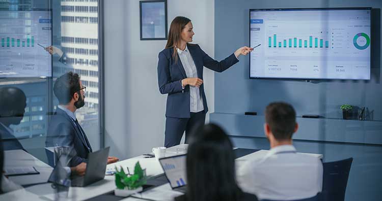 A female financial manager presents financial statistics at a company meeting.